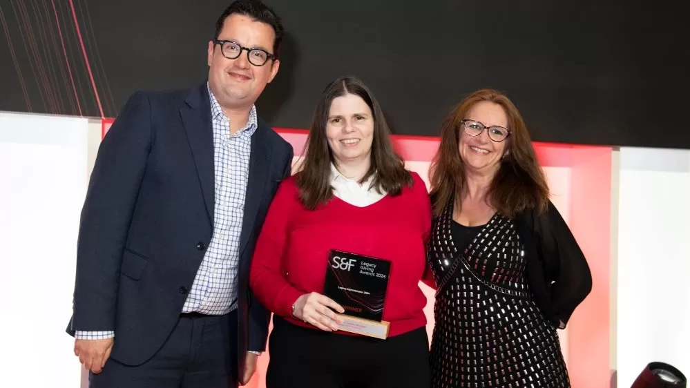 An image of three people, with Katie in the middle, holding her award.