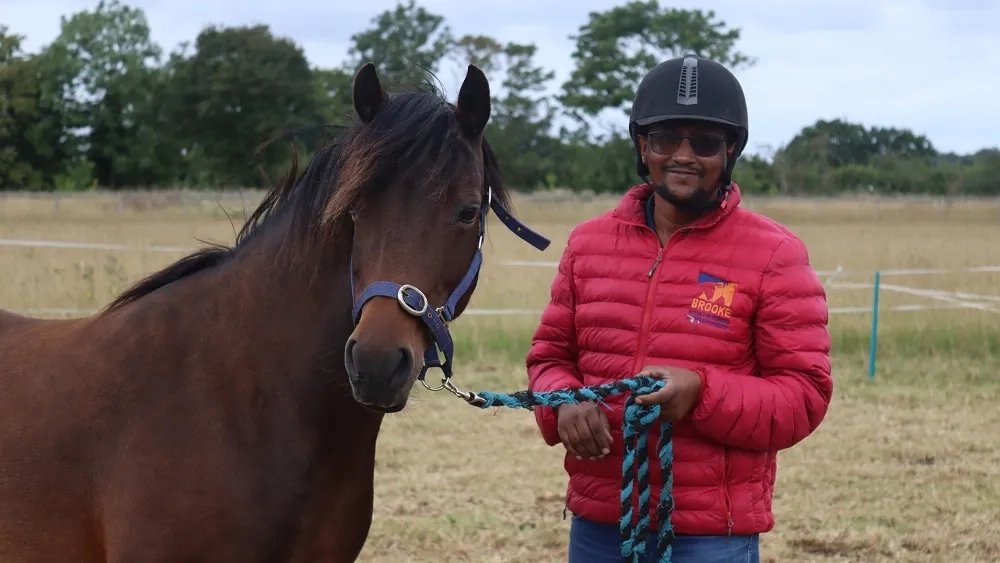 A person from Brooke charity holding a horse