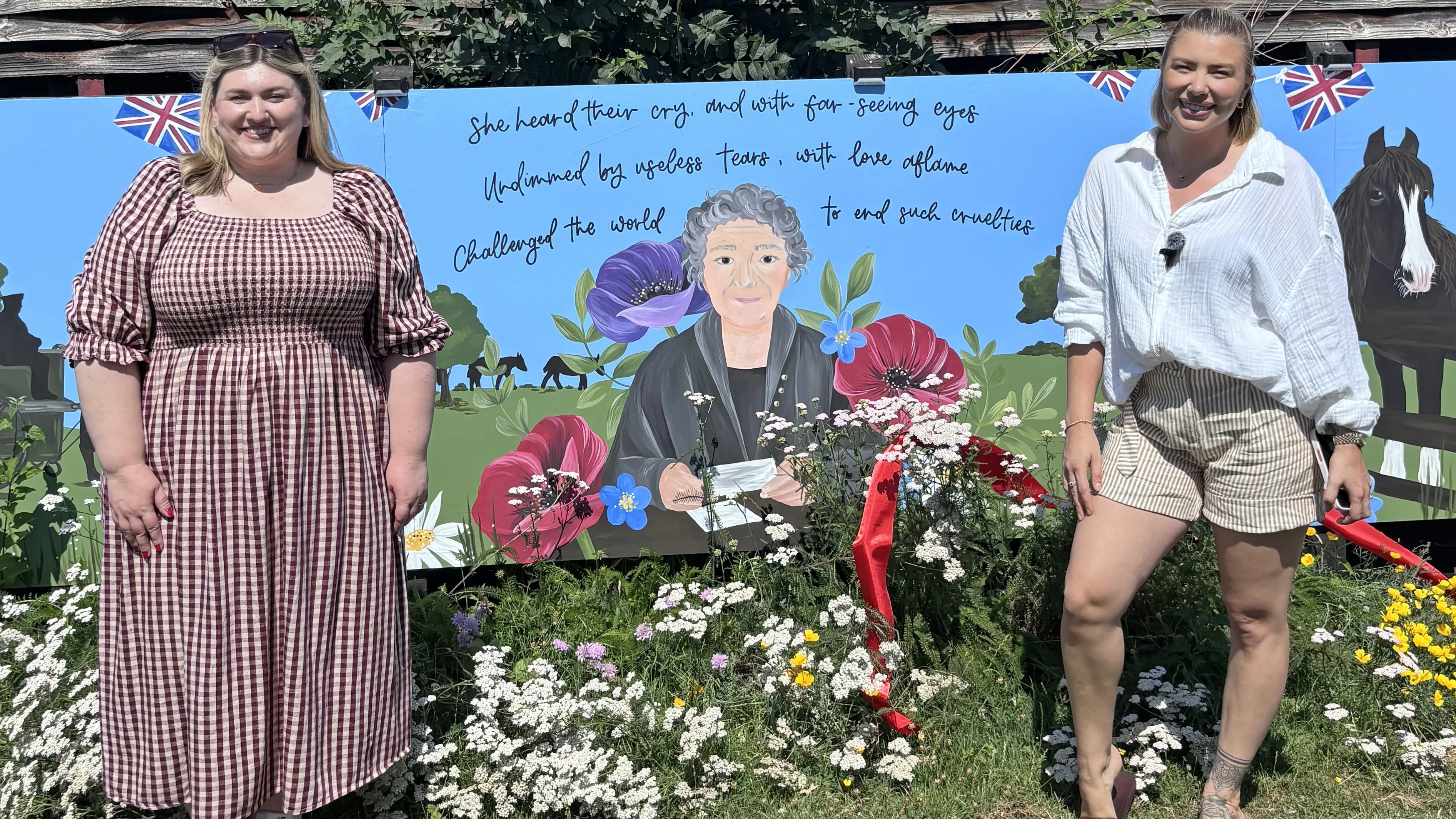 Photo of Stacey the artist and Olivia Bowen stood in front of the new mural at Redwings Ada Cole. 