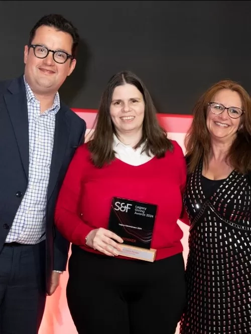 An image of three people, with Katie in the middle, holding her award.