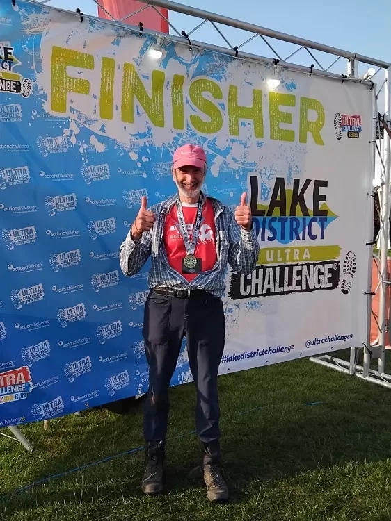 Photo of Ian wearing his finishers medal at the end of the Lake District ultra challenge. 
