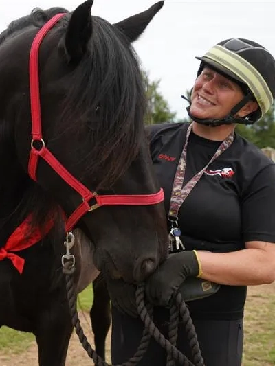 A horse with a pretty sash being held by his handler